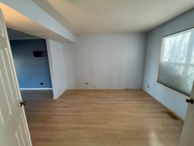 spare room featuring visible vents, light wood-style flooring, and baseboards