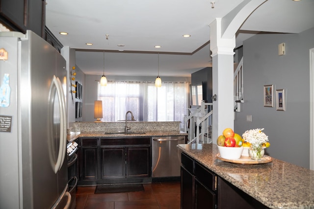 kitchen with light stone counters, stainless steel appliances, ornate columns, and a sink