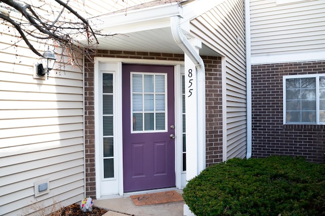 view of exterior entry featuring brick siding