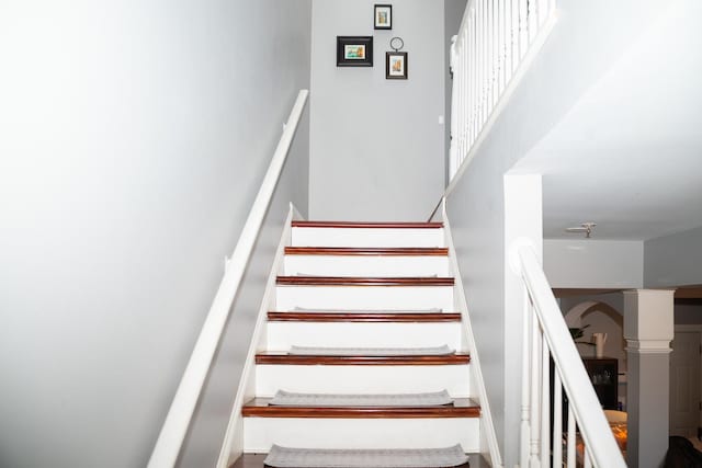 staircase with a towering ceiling and decorative columns