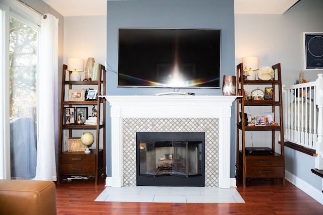 living room with a tiled fireplace, wood finished floors, and baseboards