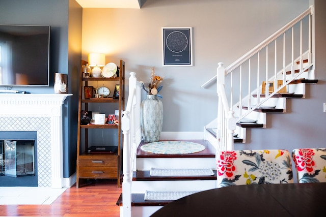 interior space with stairway, a tile fireplace, baseboards, and wood finished floors