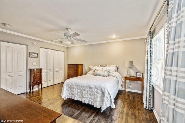 bedroom featuring ornamental molding, two closets, baseboards, and wood finished floors