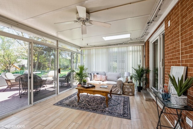 sunroom / solarium featuring ceiling fan, a skylight, and rail lighting