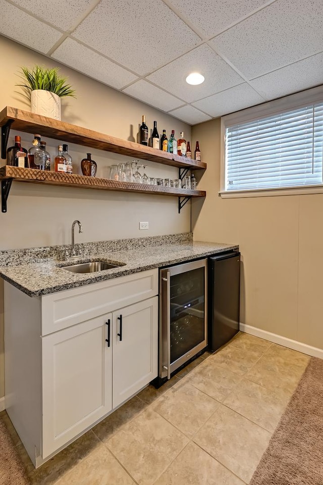 bar featuring a paneled ceiling, wine cooler, indoor wet bar, fridge, and a sink