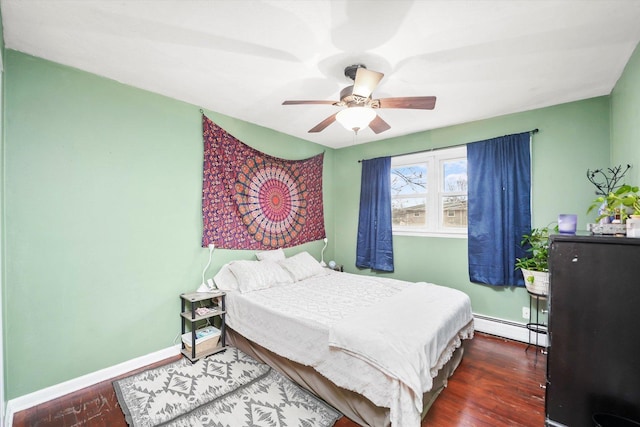 bedroom with ceiling fan, a baseboard heating unit, baseboards, and wood finished floors