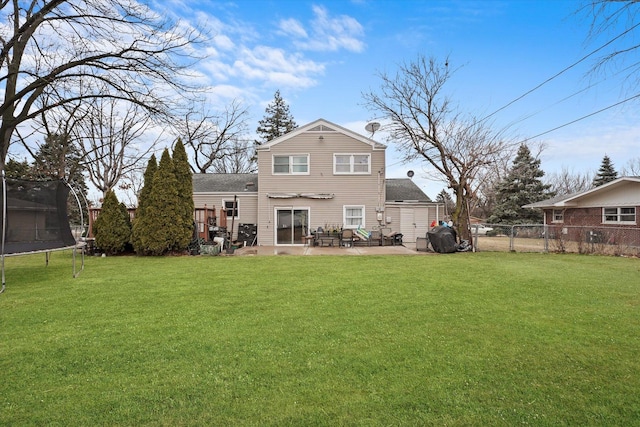 rear view of house with a gate, a trampoline, fence, a yard, and a patio area