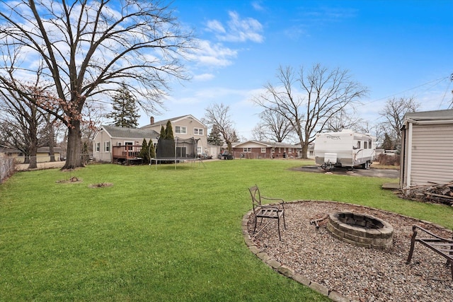 view of yard featuring an outdoor fire pit, a trampoline, and fence