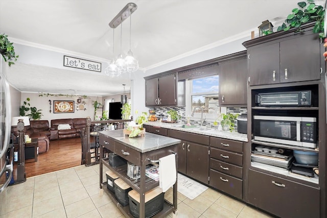 kitchen with stainless steel microwave, light countertops, ornamental molding, light tile patterned floors, and a sink