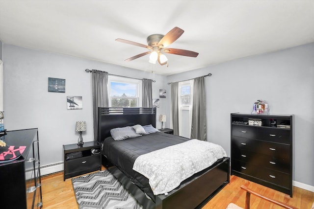 bedroom featuring baseboard heating, light wood-type flooring, and a ceiling fan