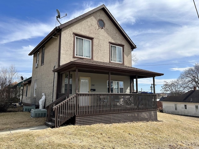 view of front of property featuring a front lawn, covered porch, and stucco siding