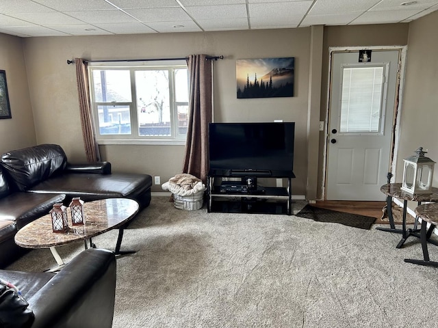 carpeted living area with a drop ceiling and baseboards