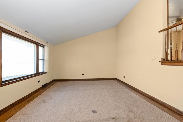 carpeted spare room with lofted ceiling and baseboards