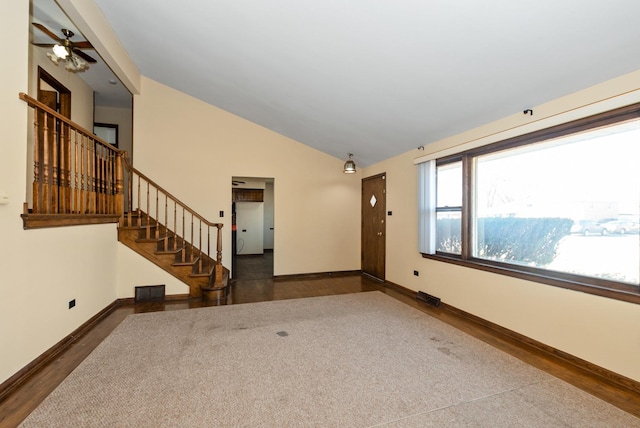 empty room featuring vaulted ceiling, stairway, visible vents, and baseboards