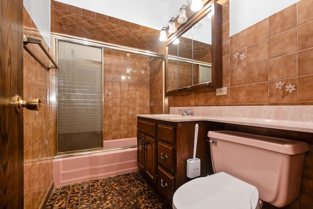 full bath featuring enclosed tub / shower combo, toilet, tile walls, and vanity