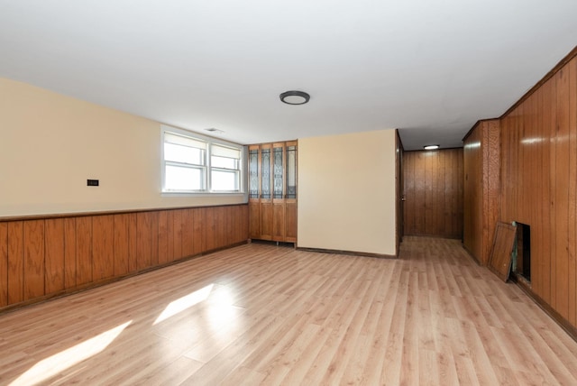 empty room featuring light wood-style floors and wooden walls