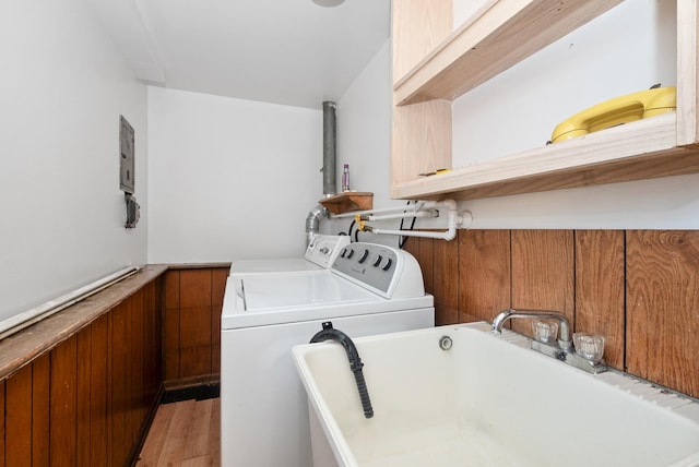 clothes washing area with laundry area, light wood-style flooring, independent washer and dryer, and a sink