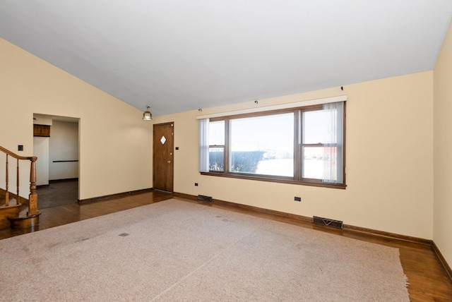 empty room with visible vents, baseboards, stairway, vaulted ceiling, and dark wood-style flooring