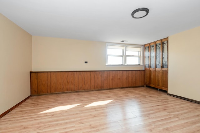 empty room with visible vents, baseboards, and light wood finished floors