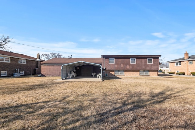 rear view of property with a detached carport, brick siding, and a yard