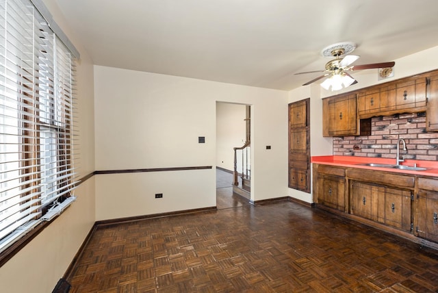 kitchen featuring a sink, baseboards, ceiling fan, and brown cabinetry