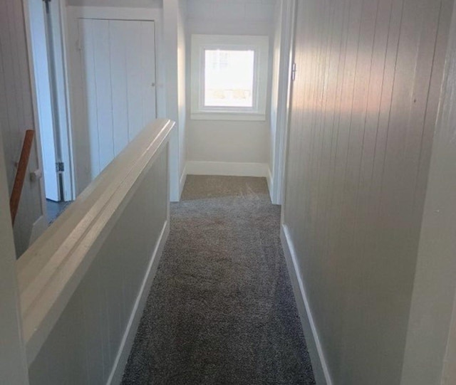 hall featuring an upstairs landing, carpet flooring, and baseboards