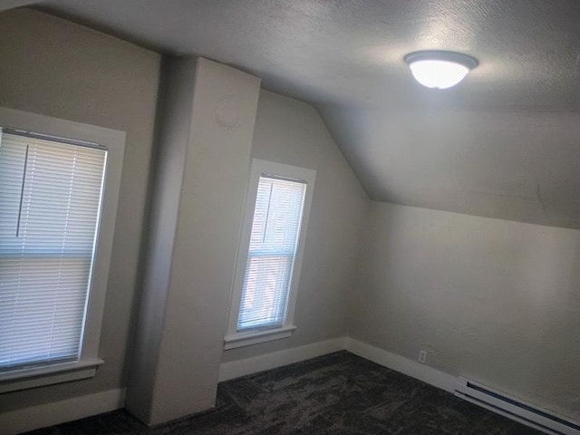 bonus room featuring dark carpet, a textured ceiling, a baseboard heating unit, and vaulted ceiling