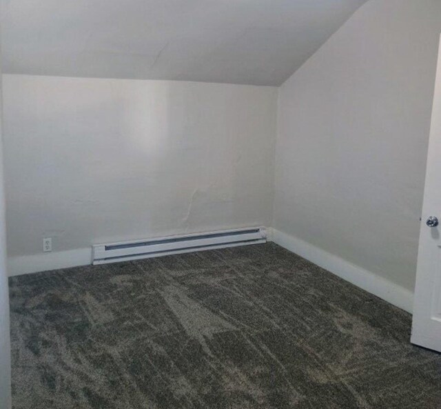 carpeted empty room featuring vaulted ceiling, baseboards, and a baseboard radiator