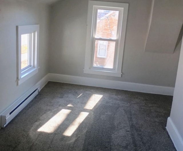 additional living space featuring a baseboard heating unit, plenty of natural light, carpet, and baseboards