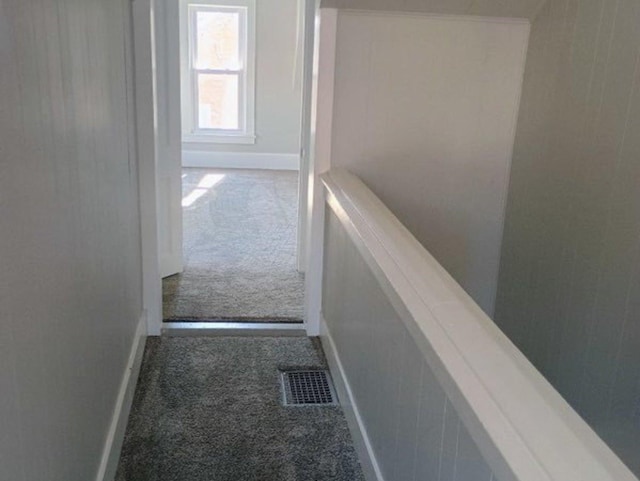 corridor with carpet, visible vents, and baseboards