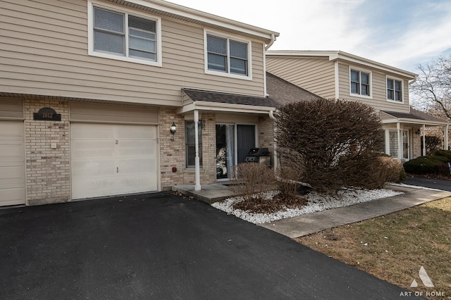 view of front of house with brick siding, an attached garage, a shingled roof, and driveway