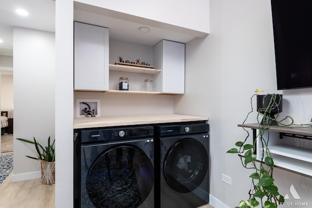 laundry area featuring baseboards, cabinet space, independent washer and dryer, and light wood-type flooring