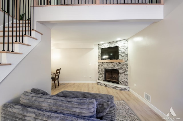 living area featuring wood finished floors, visible vents, baseboards, a fireplace, and stairs