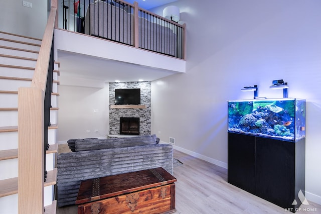 living room with a stone fireplace, stairs, wood finished floors, and baseboards