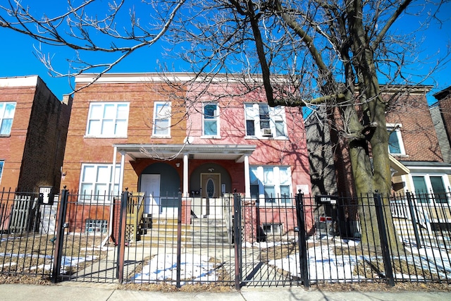 multi unit property with a porch, brick siding, and a fenced front yard