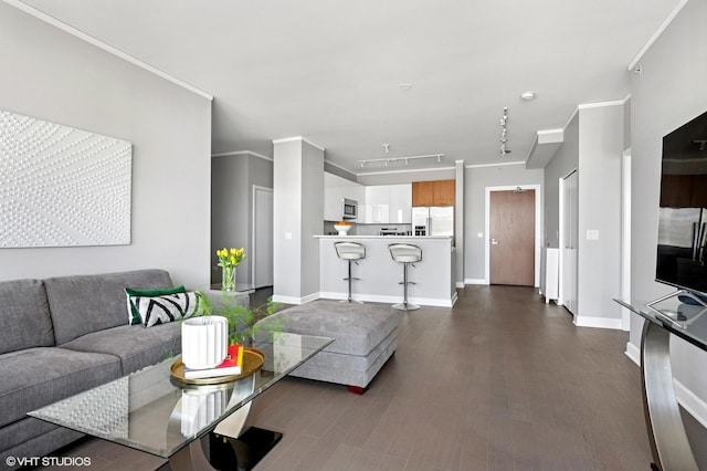 living area featuring rail lighting, baseboards, dark wood-style floors, and crown molding