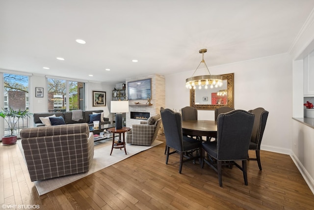 dining room with baseboards, recessed lighting, a fireplace, wood-type flooring, and a notable chandelier