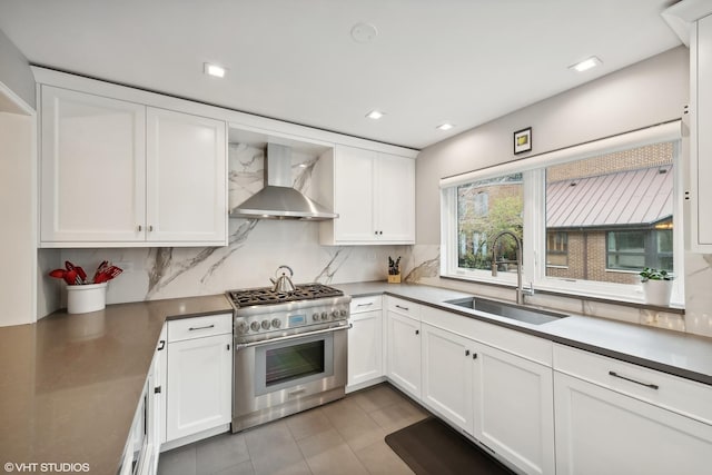 kitchen with a sink, high end stainless steel range oven, backsplash, and wall chimney range hood