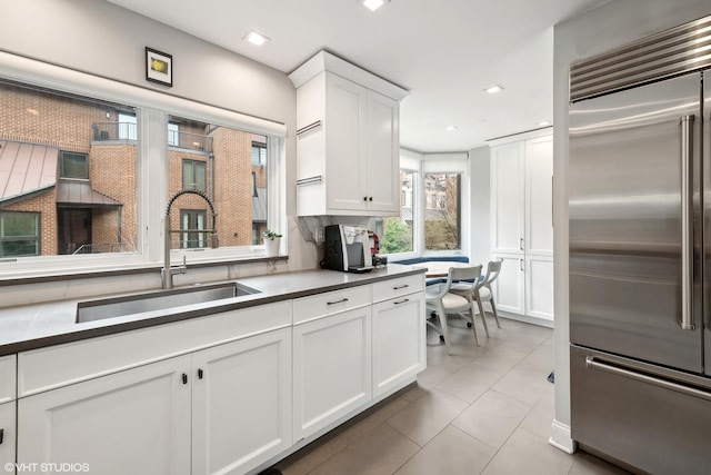 kitchen featuring light tile patterned floors, recessed lighting, a sink, white cabinets, and built in refrigerator