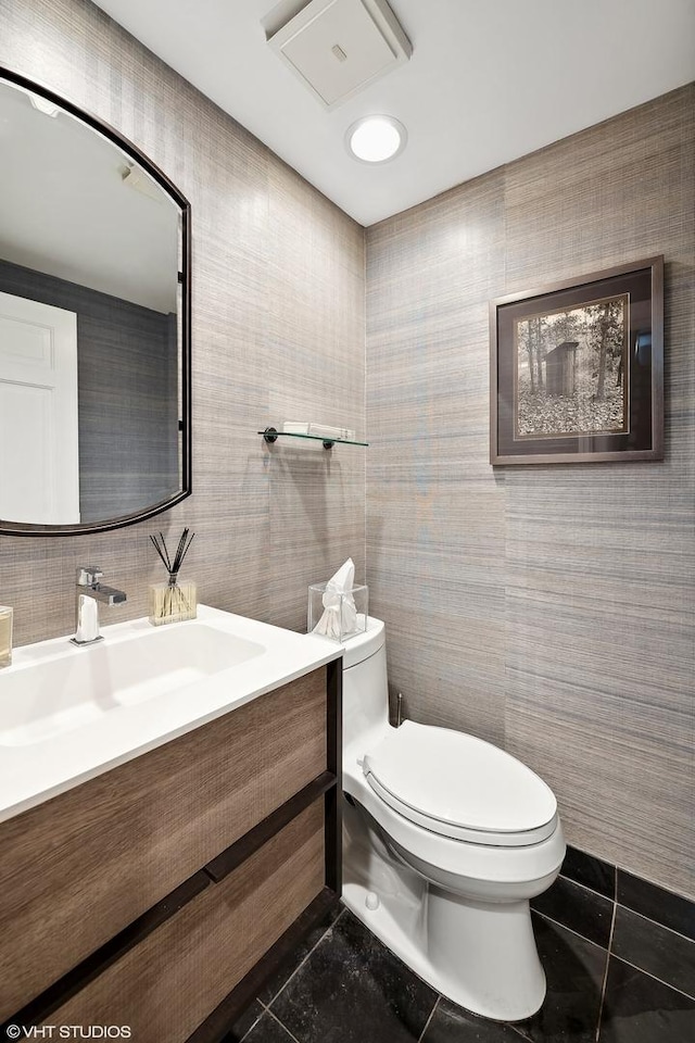 half bathroom with toilet, vanity, and tile patterned flooring