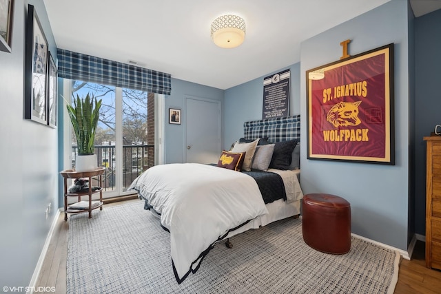 bedroom with access to exterior, wood finished floors, baseboards, and visible vents