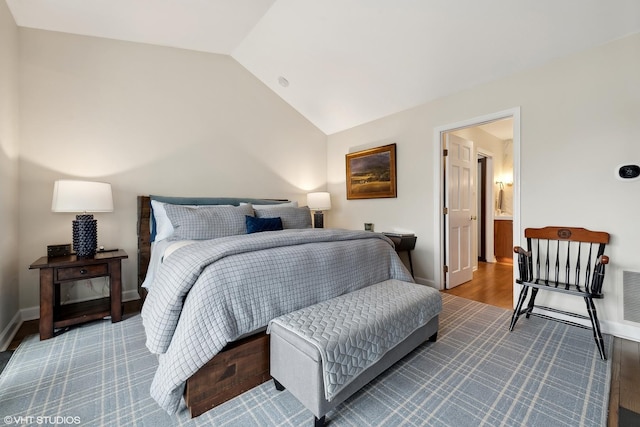 bedroom with vaulted ceiling, wood finished floors, visible vents, and baseboards