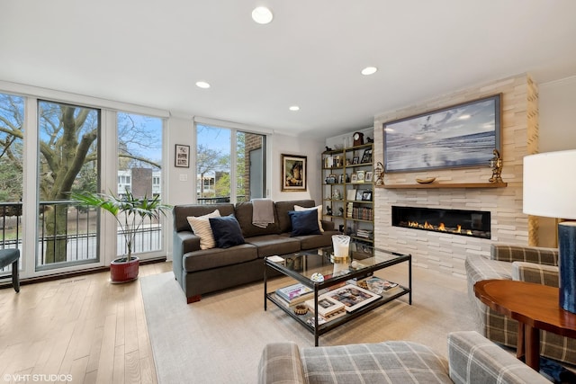 living room with recessed lighting, wood finished floors, a large fireplace, and expansive windows