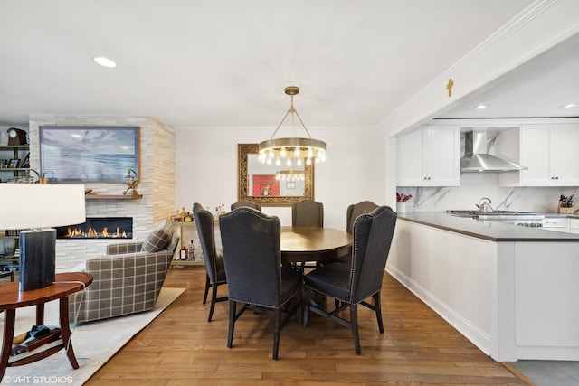 dining area featuring a notable chandelier, a large fireplace, crown molding, and wood finished floors