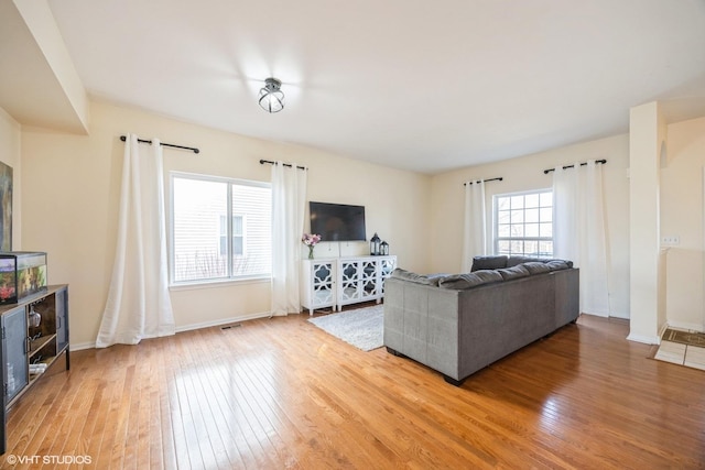 living room with visible vents, light wood-type flooring, and baseboards