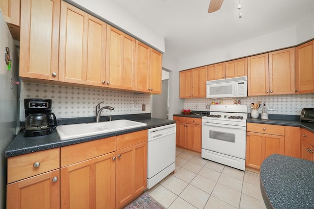 kitchen with white appliances, light tile patterned floors, dark countertops, and a sink