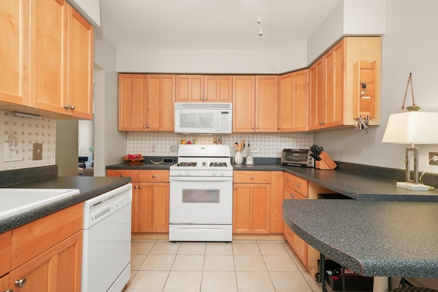 kitchen featuring dark countertops, light tile patterned floors, white appliances, and tasteful backsplash