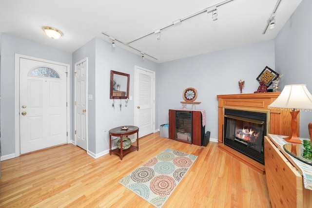entryway with baseboards, a multi sided fireplace, wood finished floors, and rail lighting