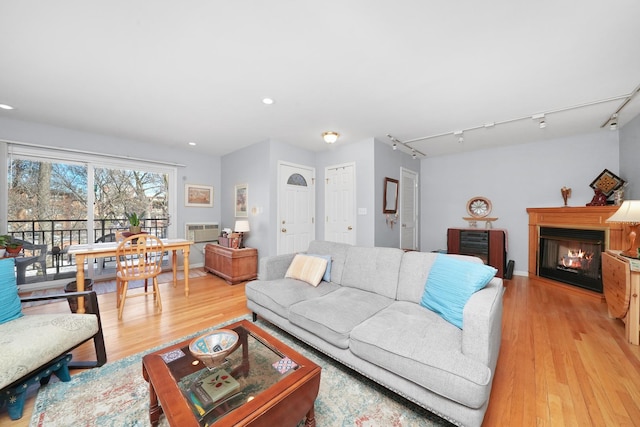 living room with a glass covered fireplace, recessed lighting, and light wood-style floors
