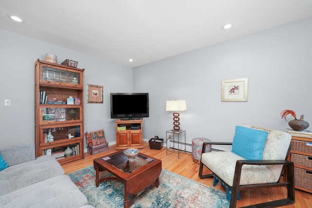 living area with a baseboard heating unit, recessed lighting, baseboards, and light wood finished floors